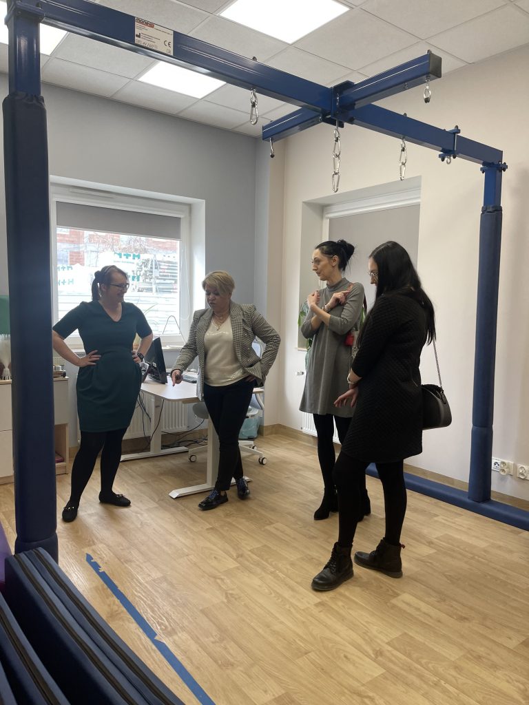 Na zdjęciu widać Panią Justynę Syroka – koordynator Punktu, Panią Dyrektor Edytę Filipczak oraz pracownika MOPR Chełm w gabinecie lekarskim w Punkcie Diagnozy., na ścianie widać tapetę ze zwierzątkami i lasem.