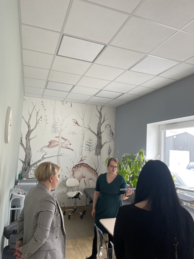 Na zdjęciu widać Panią Justynę Syroka – koordynator Punktu, Panią Dyrektor Edytę Filipczak oraz pracownika MOPR Chełm w gabinecie lekarskim w Punkcie Diagnozy., na ścianie widać tapetę ze zwierzątkami i lasem.