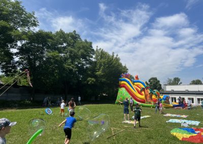 Festyn z animacjami. Dzieci biegające po trawie, puszczające bańki mydlane, strzelające z łuku