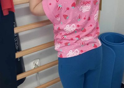 Dziewczynka stojąca przy drabince uczestnicząca w zajęciach rehabilitacyjnych