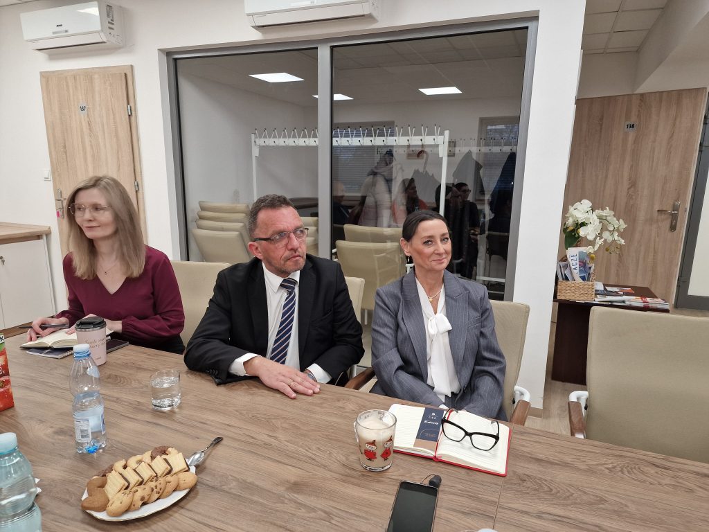 Uczestnicy szkolenia siedzą przy stołach i słuchają prowadzącego szkolenie.